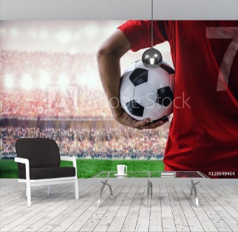 Picture of Soccer football player in red team concept holding soccer ball in the stadium